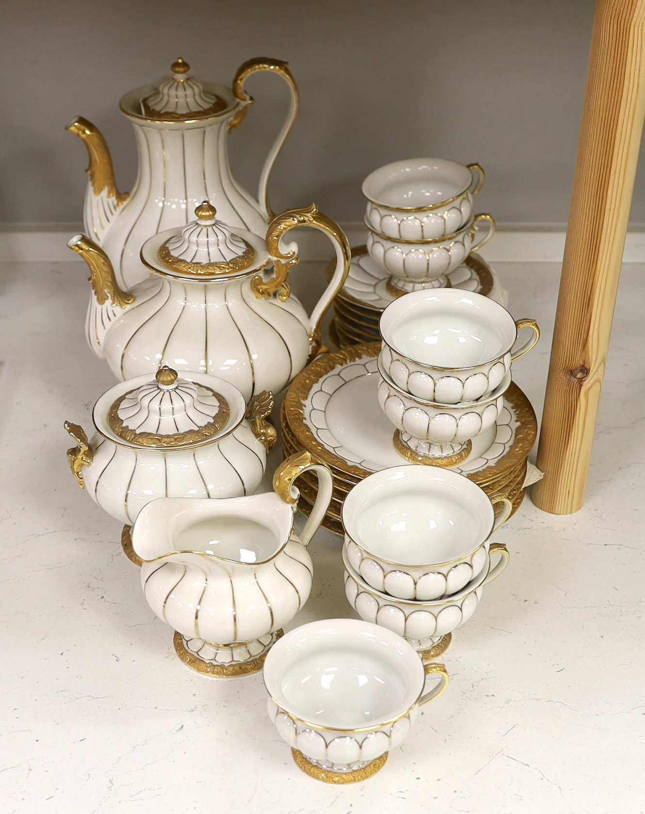 A Meissen gilt and white glazed porcelain tea service, mid 20th century, comprising a teapot, coffee pot, sugar bowl, side plates and seven cups and saucers, coffee pot 28cm